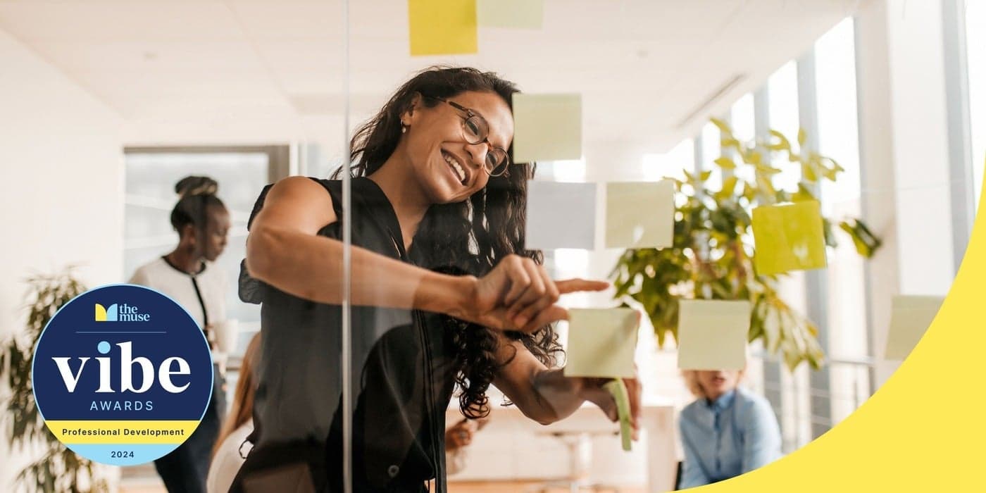 A person smiling and organizing sticky notes on a glass pane in an office.