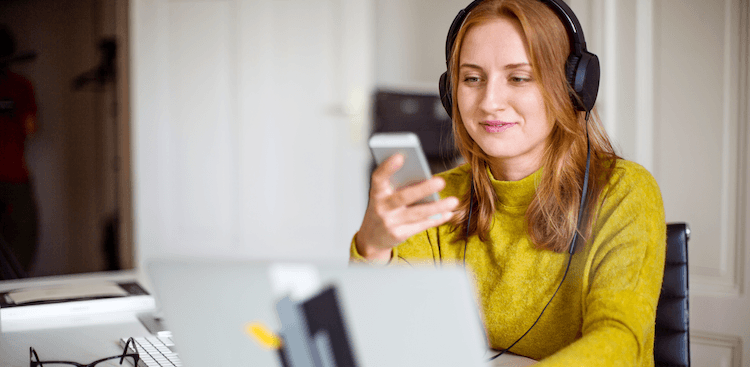 person working on a laptop and looking at a cell phone